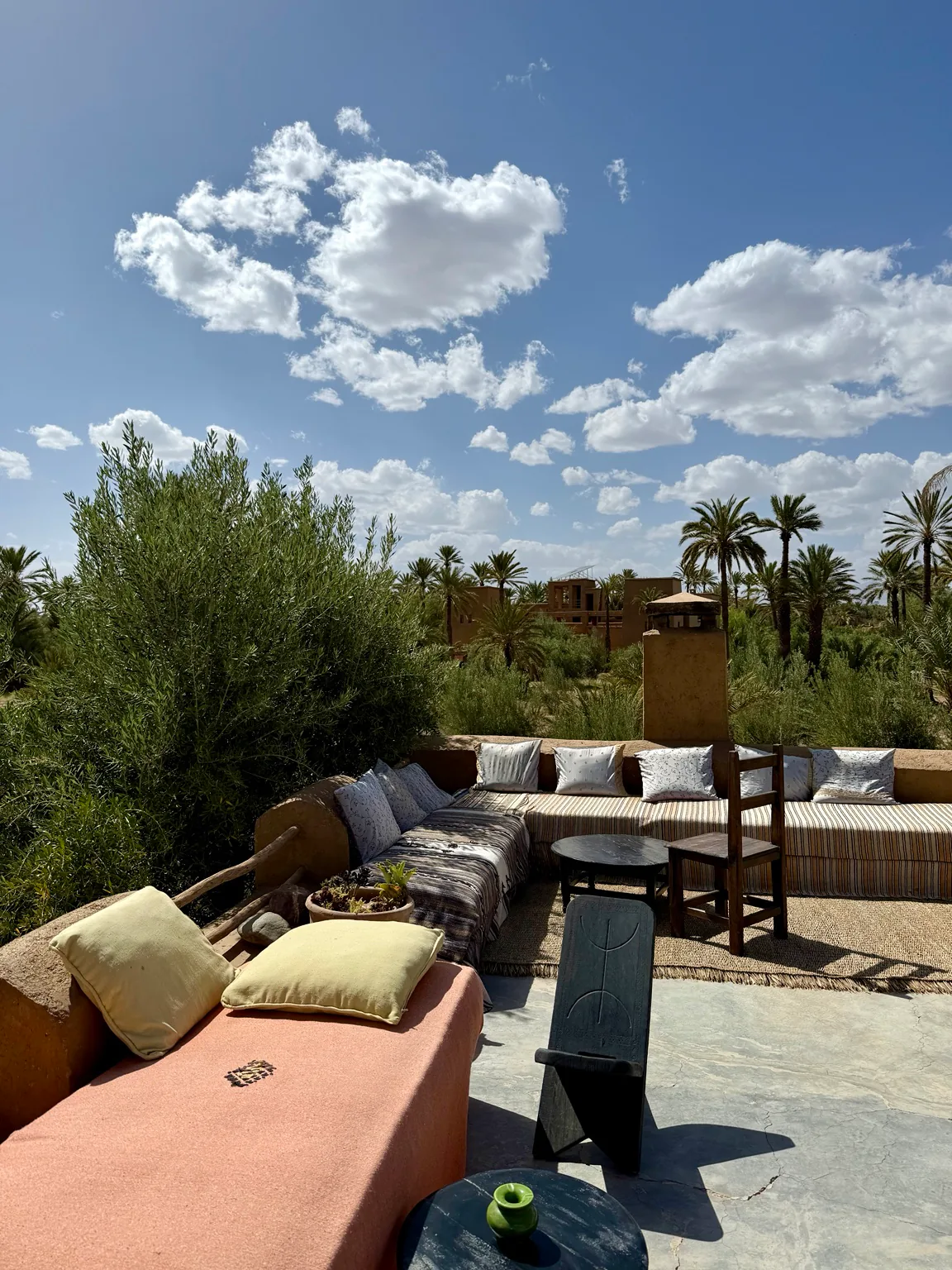 A sunlit terrace overlooking palms beneath a wide Moroccan sky