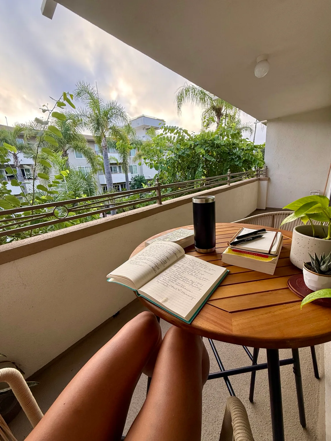 A journal open on a quiet balcony surrounded by morning light and greenery